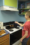 Sixth-grader Chris Evans prepares grilled cheese sandwiches, his specialty, for the group.