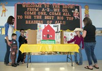 The students dressed up for the event to match the book they chose. Brayden Barker, a second-grade student shows his mom, Tina Catchings, and his brother, Bryce Barker who is in kindergarten, his Harry Potter and the Sorceror’s Stone project. Bryce’s book was How to Train Your Dragon 2. At the same table, fourth-grade student Kasey Hudson discusses her project with her mom, Lori Hudson.