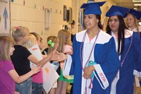 Seniors Chantal Branham (front) and Leydy Moreno give high-fives to Adair County Primary School second-graders, l-r, Sophie Eaton and Koda Sutt. Members of the Class of 2016 paraded through the hallways of the lower schools, greeted by faculty, staff and future graduates, many bearing hand-crafted congratulatory signs.