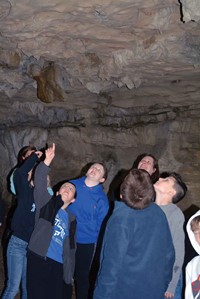 Third-grader Eli Howard points out a ceiling feature in the X-Cave to classmate Maddex Hansen and others. In another cavern in the system, students saw a hibernating bat and learned about the white-nose syndrome disease that threatens bat populations in caves across the U.S.