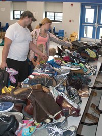 Jeffrey and Amanda Tackett look at shoes with their three children. In addition to used shoes, each student who attended was given a card to receive a free pair of new shoes that had been donated by local churches through a “Shoes in the Pews” program. 