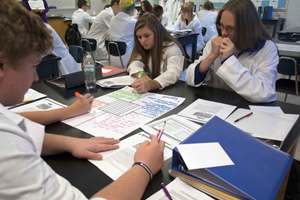 L-R, Clay Morris, Haleigh Adkins and Andrew Delancy work on a tabletop analysis of a text – the four sections of the central paper represent the different roles each student has in the exercise.