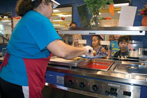 Tolliver Intermediate food service staff member Janet Potts makes sure students know that the marinara sauce was made that morning from tomatoes grown 15 miles from their school. 