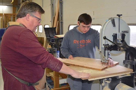 Instructor Kevin McKnight, left, watches as Ryan  Hughes cuts wood during carpentry class. 