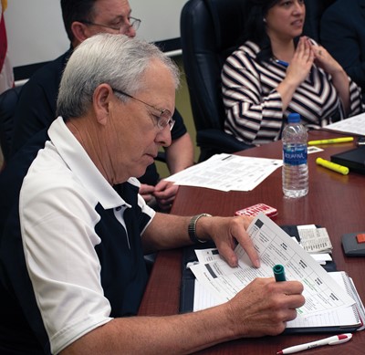 Russellville Independent school board member Joe Sparks checks off a box on the rubric scoring for one of the panel review presenters.