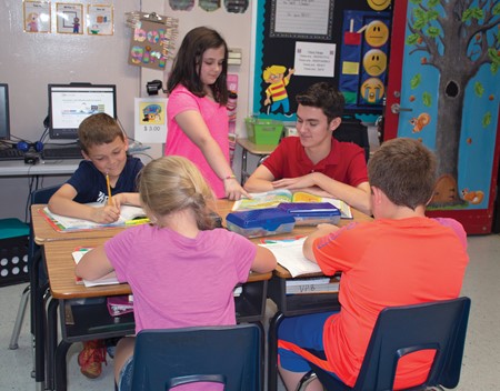 Brevin Charles (back right) helps a student with an assignment as part of his internship in Vickie Pendygraft’s second-grade class at Mercer County Elementary. 