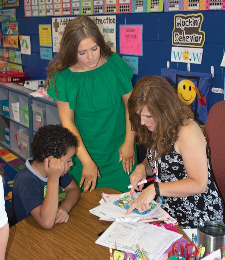 Mackenzie Ezell watches as her mom, Mercer County Elementary first-grade teacher Jennifer Ezell, checks an assignment . Mackenzie interned in her mom’s class as part of the high school’s Principles of Teaching class.