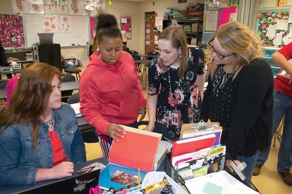 Kaysie Adkins, left, shows her student-teaching binder to Trinity Yeast, teacher Miranda Goodlett and Julia Weaber during Goodlett’s Principles of Teaching Class. All three students are juniors at Mercer County Senior High School.
