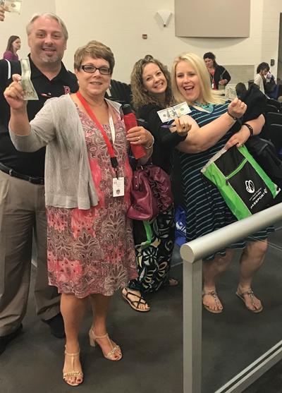 Teachers Todd Calvert (left), Debbie Jones, Tiffany Espelage and Ali Orme proudly show off their $100 bills at the district’s opening ceremony. 